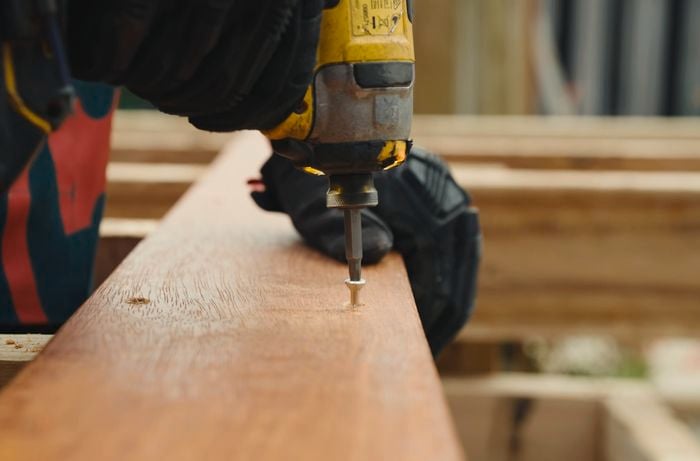 Person using a drill to screw screws into timber