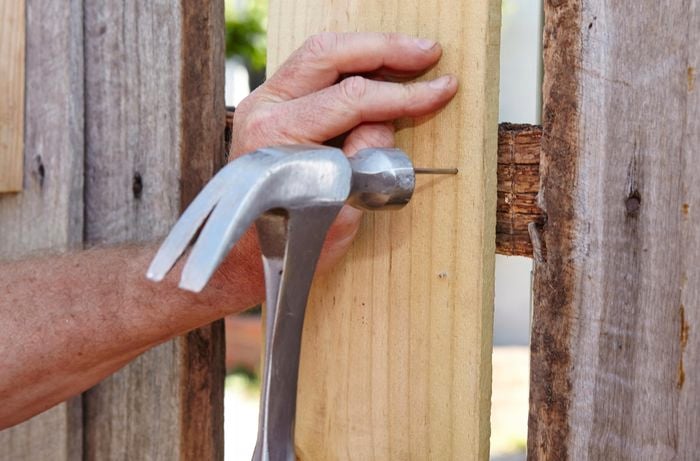 A new fence paling being nailed to the fence with a hammer and nail