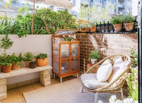 Apartment courtyard with raised garden beds, potted plants and a stone bench.