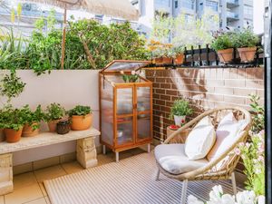 Apartment courtyard with raised garden beds, potted plants and a stone bench.