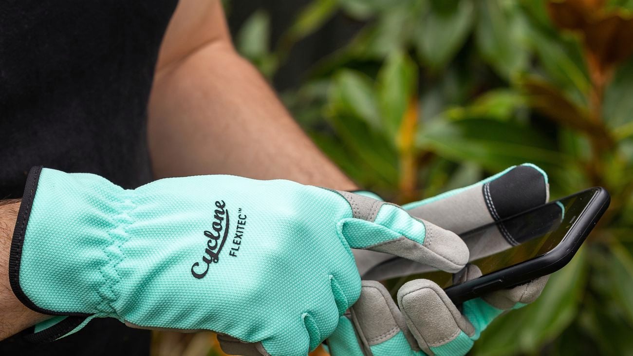 Hands wearing teal gardening gloves hold phone