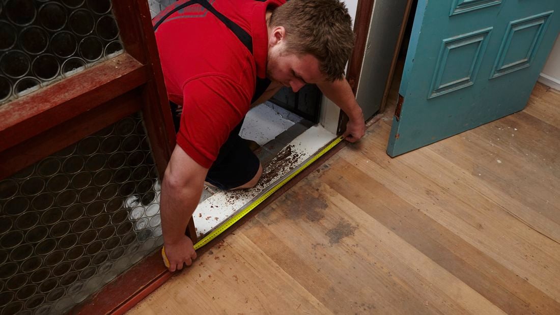 Person measuring the base of a door cavity.