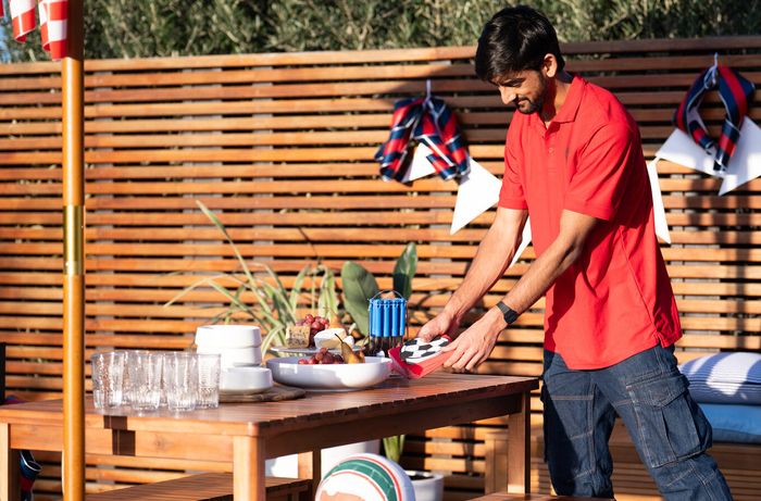 Setting an outdoor dining table with serving dishes and game-day themed decorations.