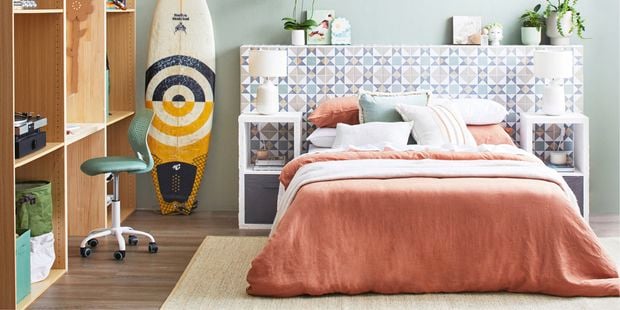 Styled bedroom with desk and surfboard.