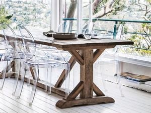 Wooden table with clear plastic chairs. A balcony is in the background.