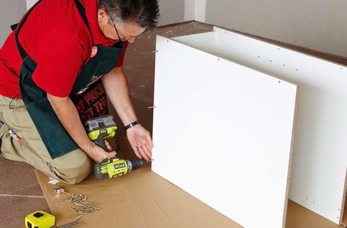 Person attaching base panel of cabinet