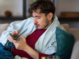Man lying on a couch looking very relaxed and reviewing his phone