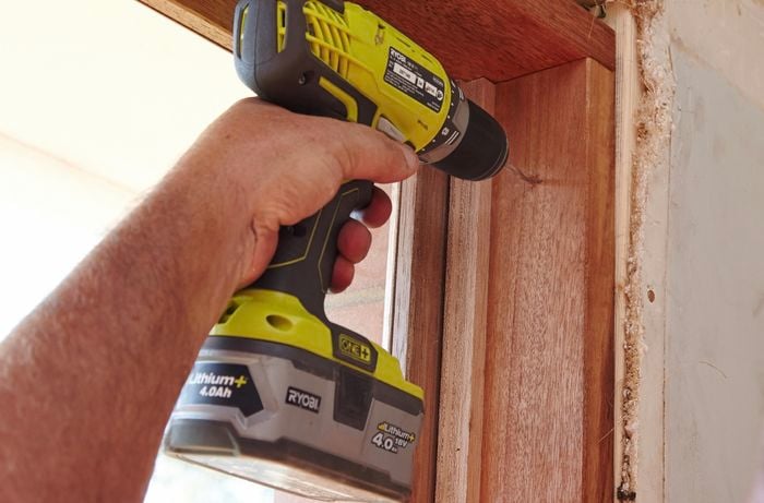 Drilling pilot holes at the top of the window frame