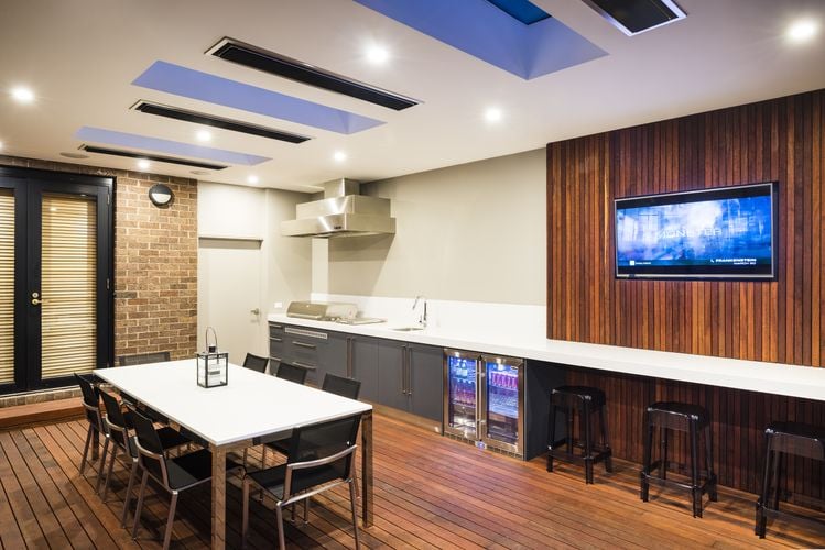 An enclosed deck entertainment area complete with roof mounted heaters, bar fridge and sink