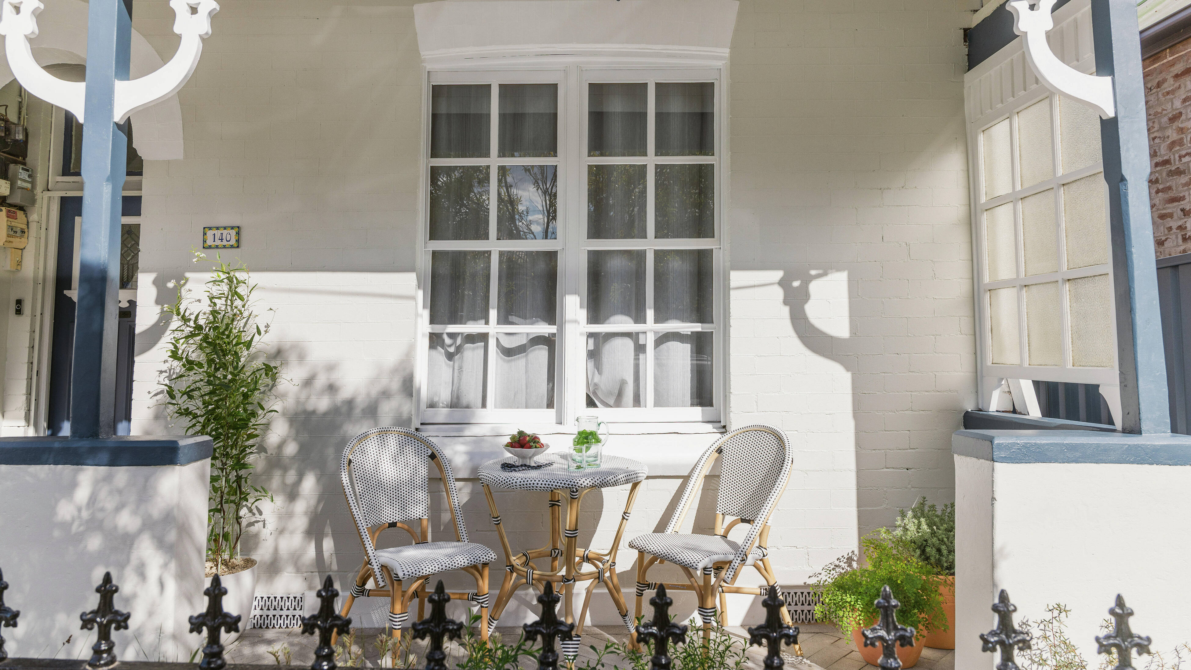 Freshly painted heritage home veranda with outdoor seating and potted plants.