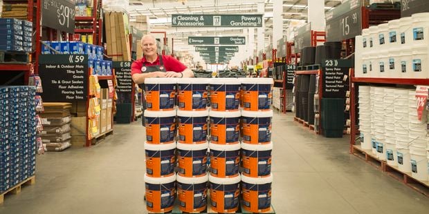 Team member standing behind a stack of paint cans.