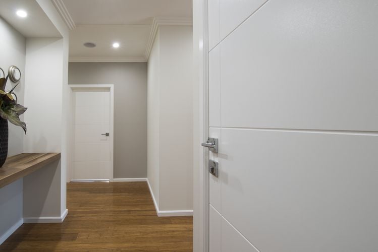 A white hallway with wooden floors and several doors to other rooms