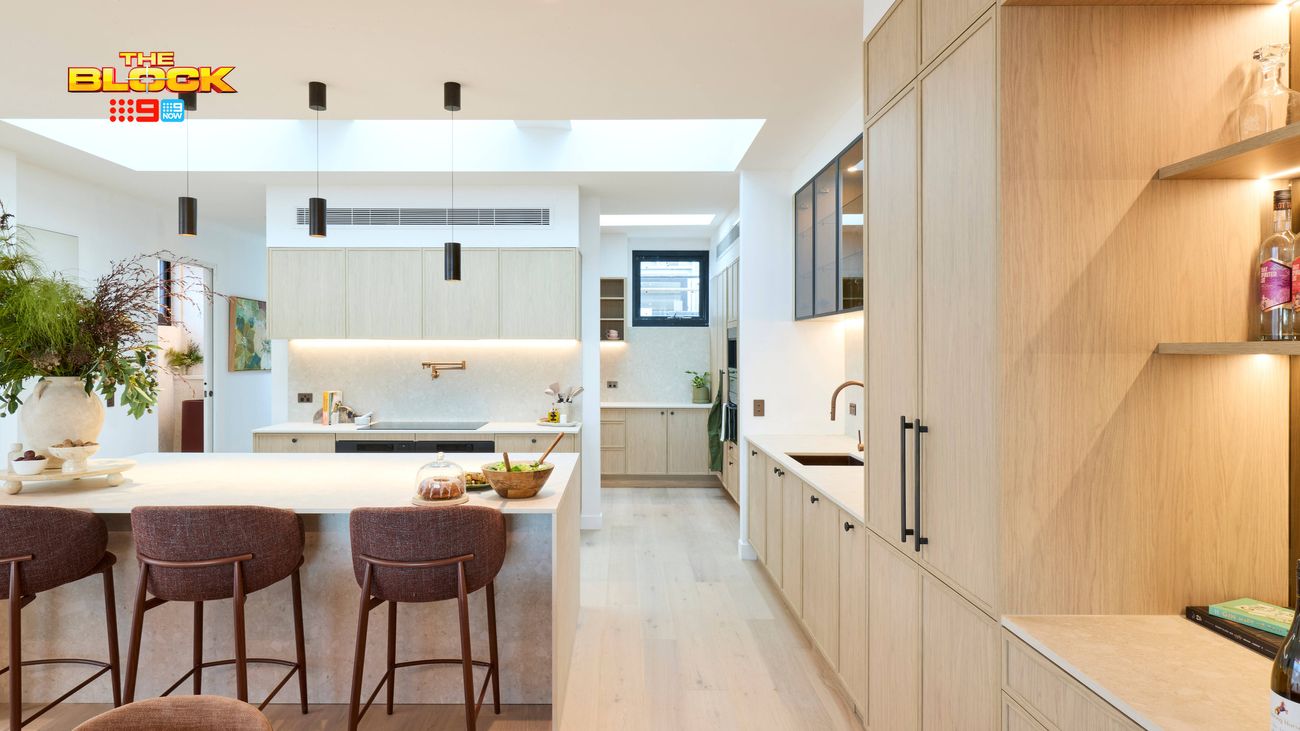 Modern kitchen featuring a large island bench with bar stools, light timber cabinetry, pendant lighting and built-in shelving.