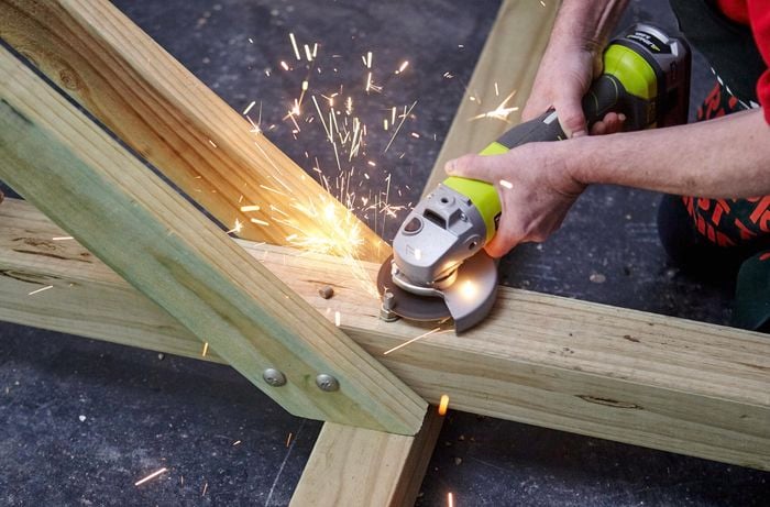 Person using handsaw to cut extra bit of screw off.