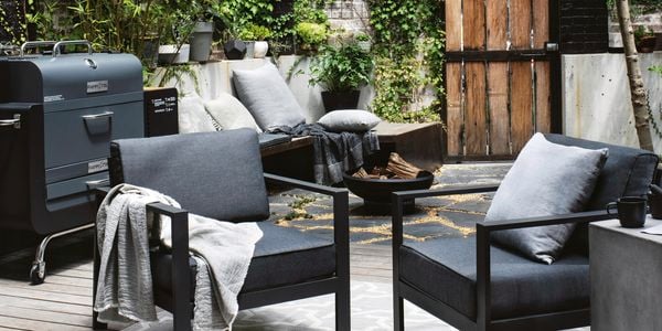 Outdoor lounge with two chairs and a BBQ next to it.