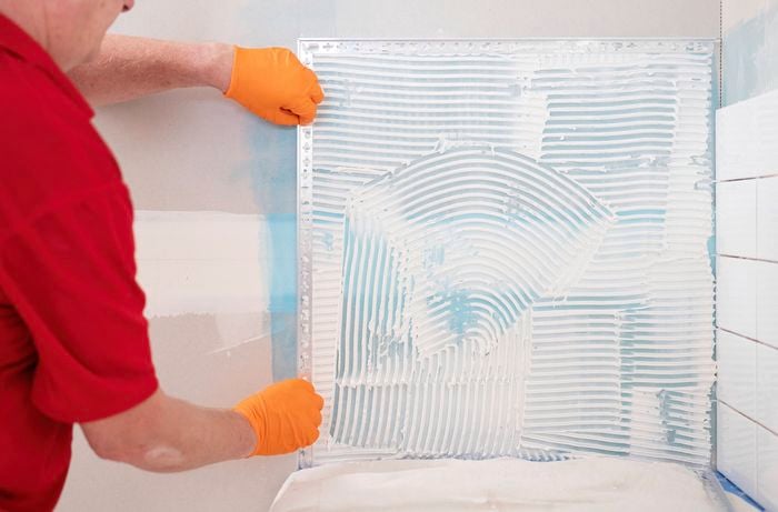 A person in a red shirt is wiping away any dust or adhesive residue using a damp cloth.  ]