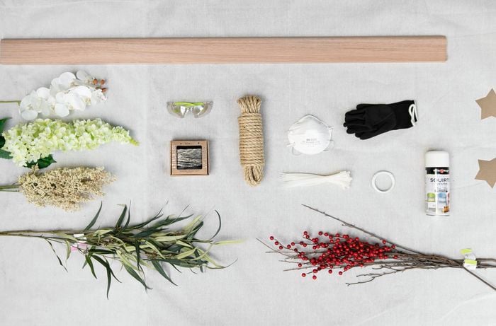 Tools and materials flat lay on deck including timber, green foliage, rope and paint