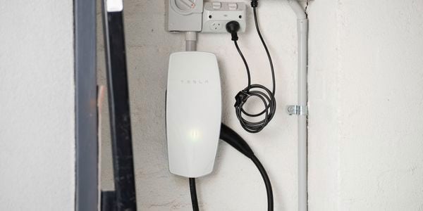 A Tesla Wall Connector is mounted on a wall, neatly installed with connected power cables. 