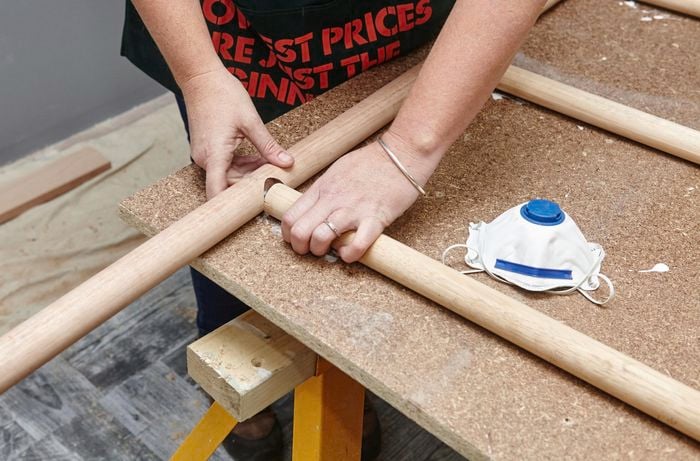 Person inserting ladder rungs into outer part of ladder.