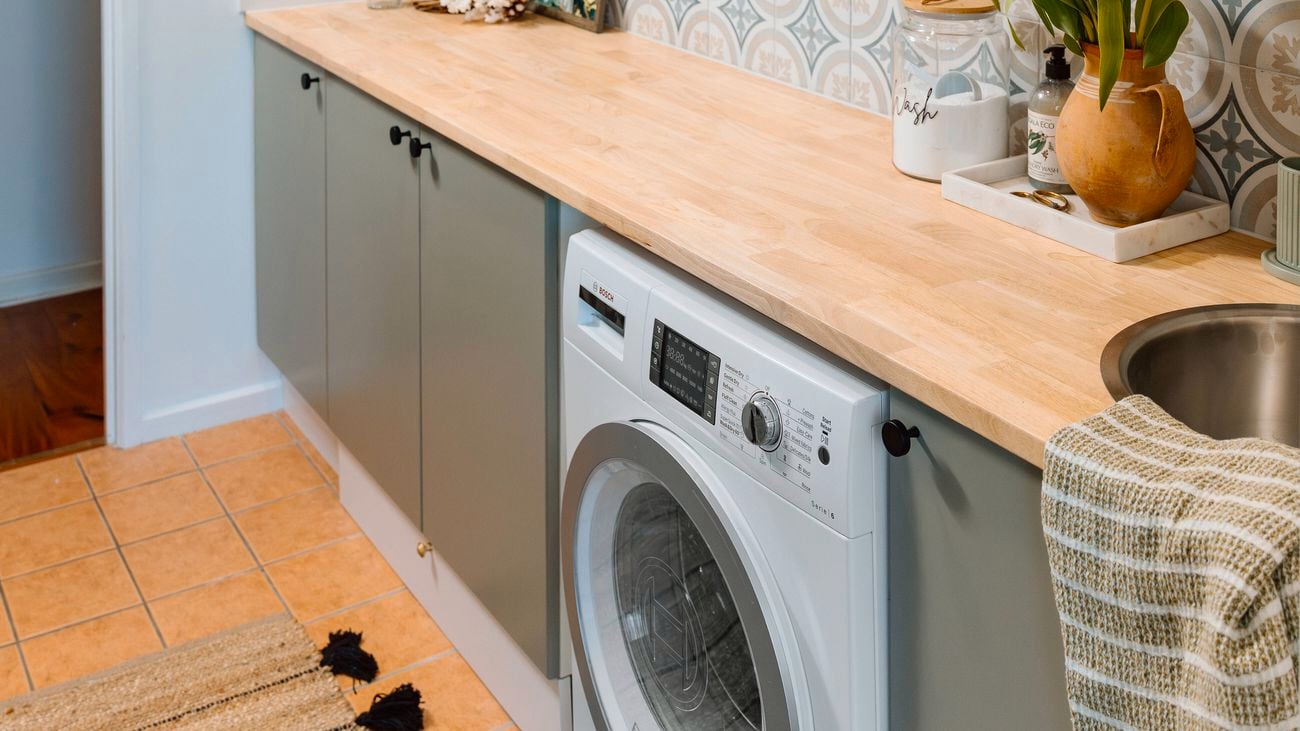 Updated laundry with timber bench tops, timber shelvomg and mosica green and blue wall tiles