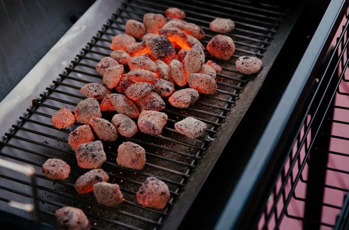 Charcoal briquettes glowing red hot on a smoker rack 