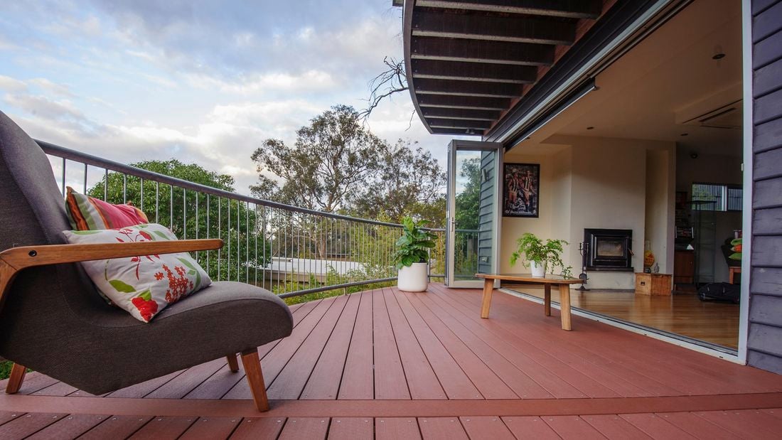 A deck leading out from a living space separated by bay windows
