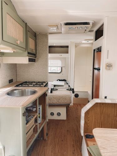 The interior of an RV caravan kitchen, with green cabinetry.