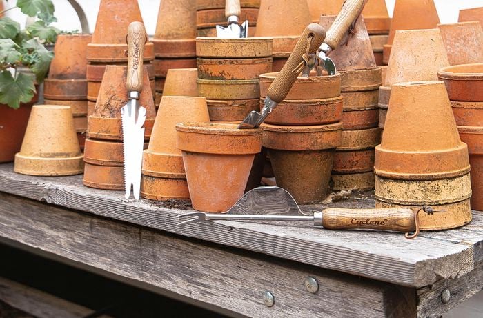 Garden hand tools placed in terracotta plant pots