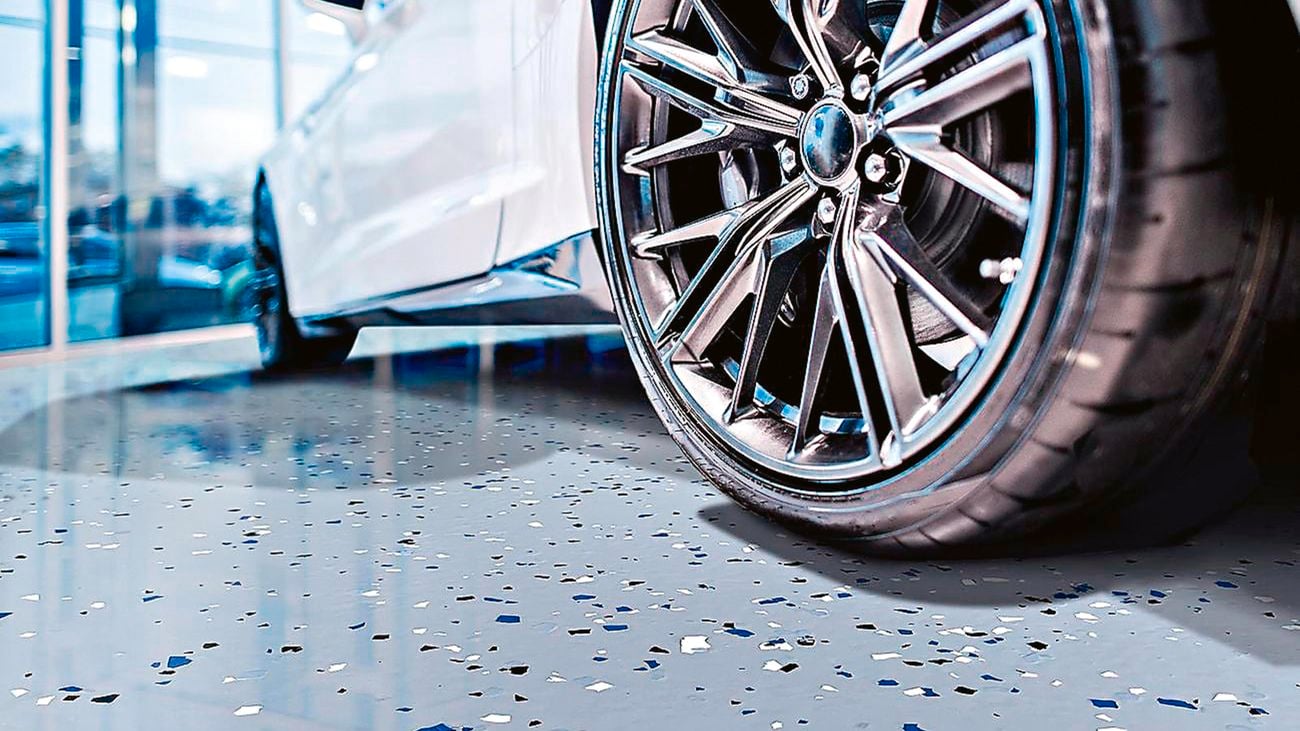 Close up of a car wheel on a speckled epoxy garage floor