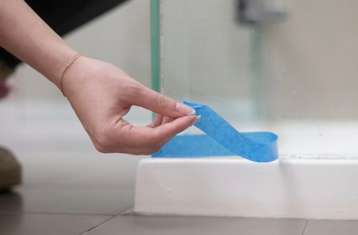 A person is carefully peeling off masking tape from the surface.