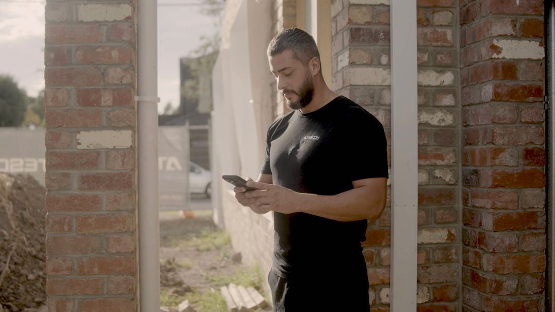 Person looking at their phone whilst standing in-front of a building site.