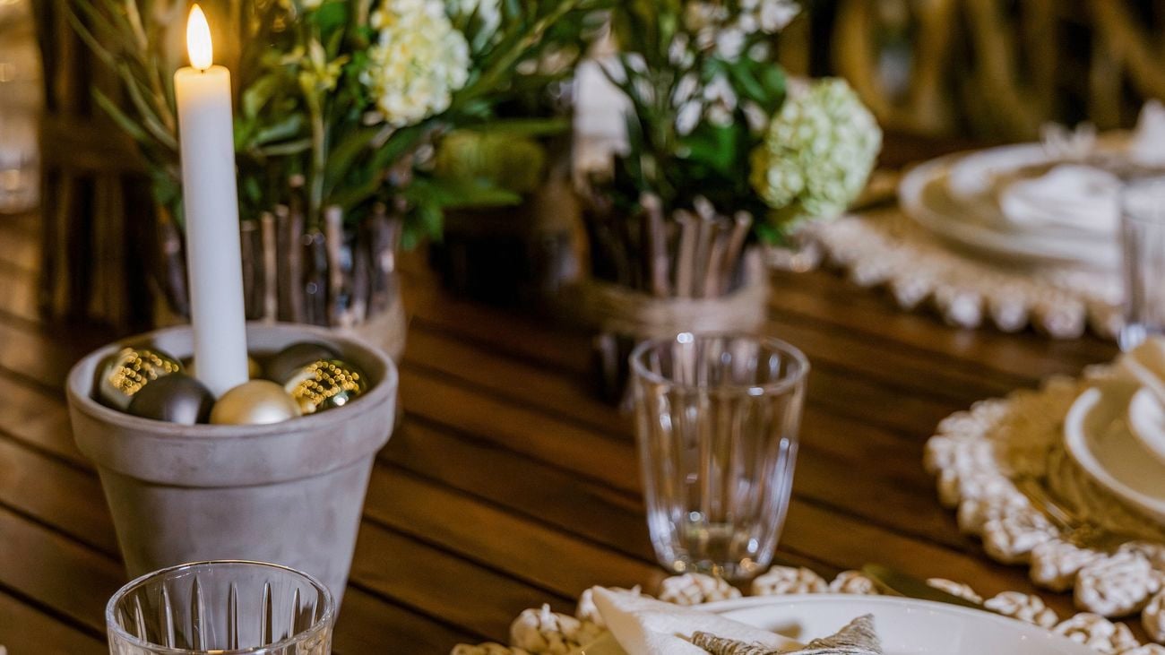 Candle centerpiece and festive place settings on a wooden outdoor dining table.