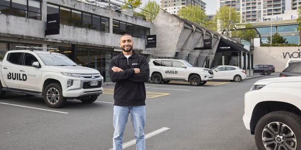 Trade person with his arm crossed, smiling with his trade Ute in background