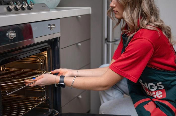 Clearing out the oven by taking trays out.
