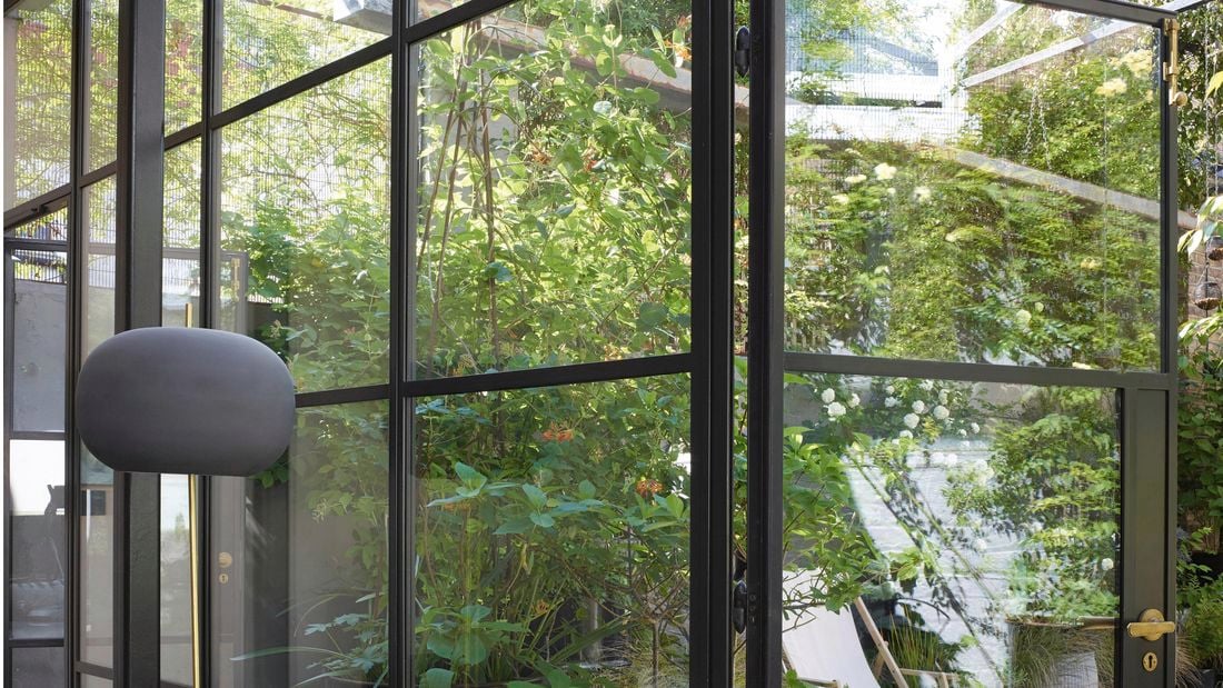 Window adorned with black aluminium window frames and pendant lights hanging from the roof.