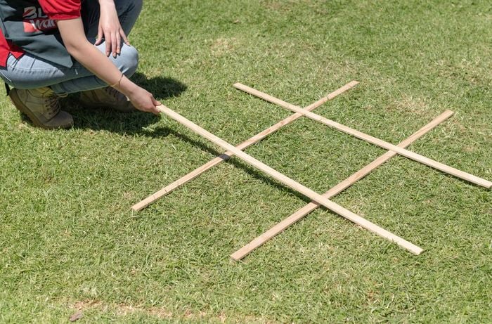 Person laying timber down to complete a grid shape.