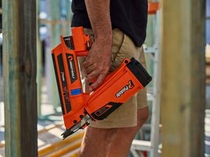 A man shot from the waist down holds the Paslode FrameMaster NightWolf on a construction site.