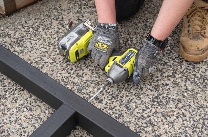 Person assembling the frame using a drill.