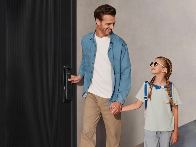 Person using the fingerprint scanner on a Philips Smart Lock installed on a front door.