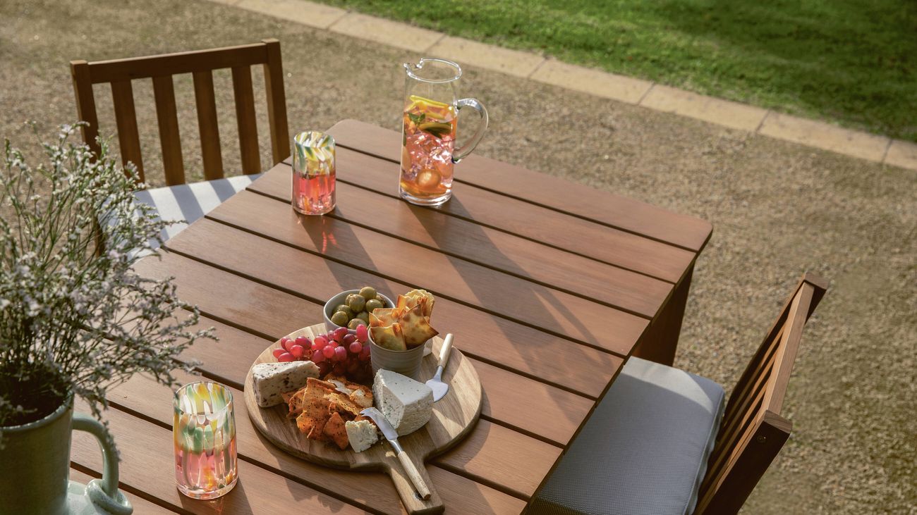  Timber outdoor table with drinks, cheese board, and snacks.