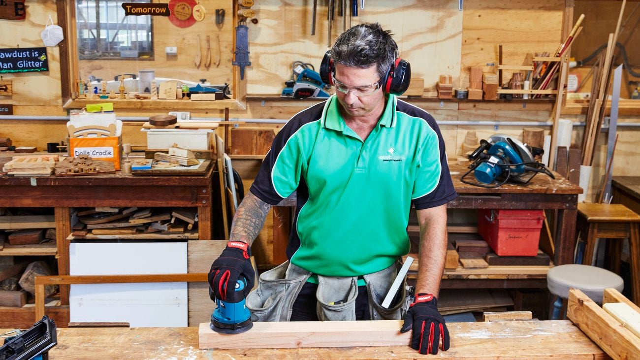 A builder is his workshop using a Makita sander