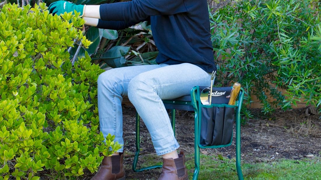 Person sitting on stool tending to garden