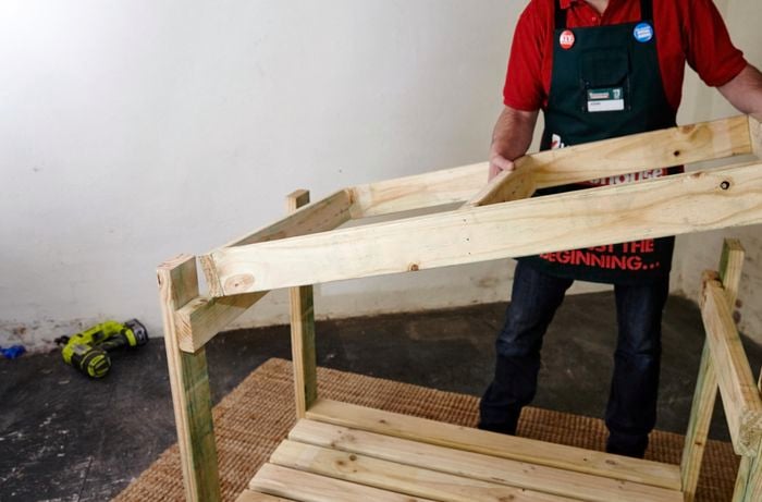 A person lifting a top frame into place on a bottom frame