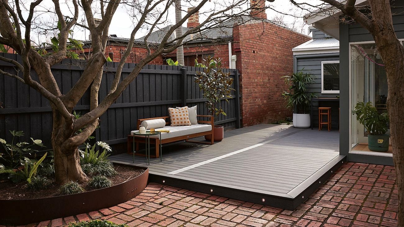 Shot of a backyard with deck with black wooden deck boards and outdoor furniture