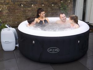 Family sit in a spa bath with in their yard with daughter and son and the front and mother and father at the back