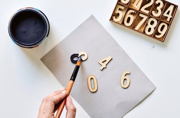 Aerial view of a woman’s hand painting craft numbers