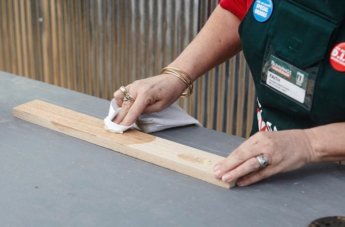 A person applying oil to a piece of timber with a rag