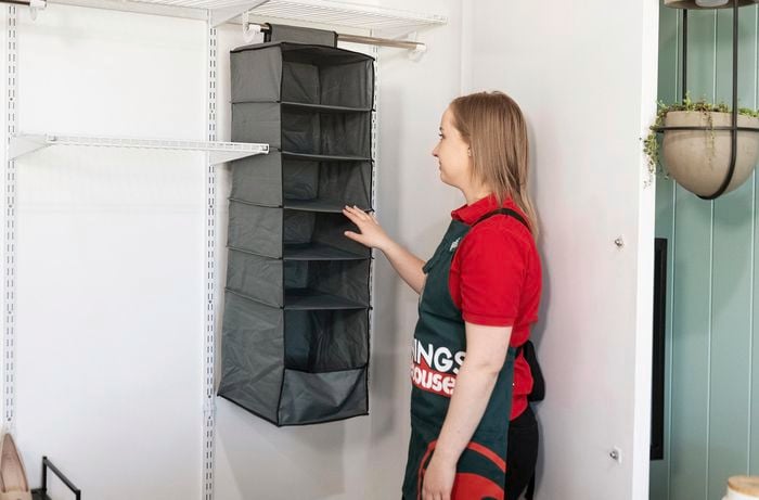 A person looking at a hanging shoe rack inside a wardrobe