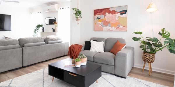 Living room with grey couches, hanging plants and artwork.
