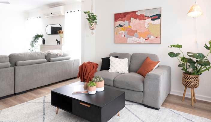 Living room with grey couches, coffee table and rug.